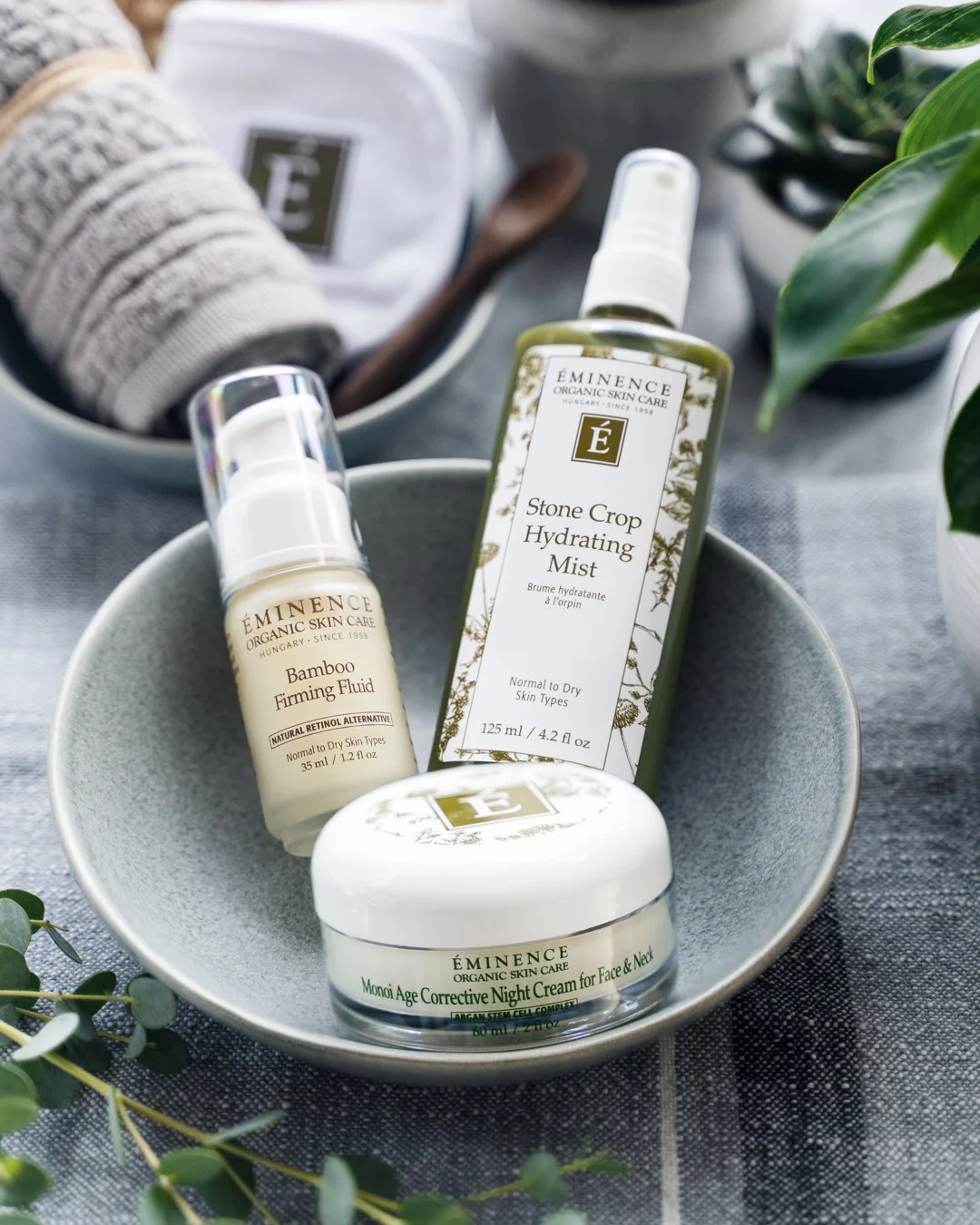 Éminence Organic Skin Care products styled on a wood board with fresh botanicals